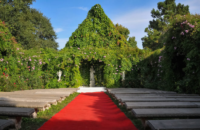 Photo of the green lush venue with a red aisle and stone seating arrangements. 