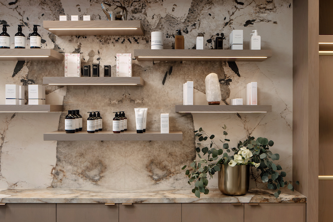 Shelves against a marble wall with skincare products for sale. 