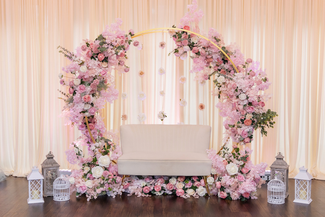 A gold circle decorated with pink florals with a cream couch inside it. 