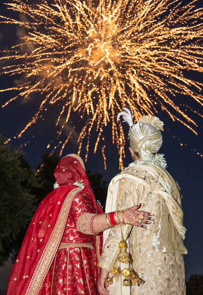 The bride and groom looking up at fireworks. 