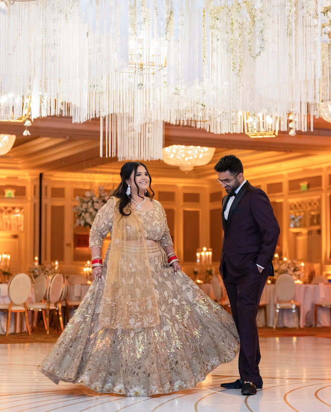 The bride and groom on the white and gold dance floor at their reception. 