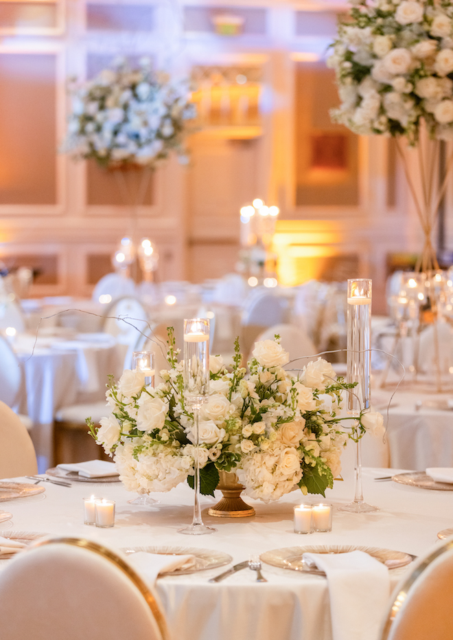 White floral centerpieces with floating candles at a wedding reception at Houston Marriott Sugar Land. 