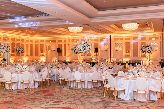 The ballroom at Houston Marriott Sugar Land with white circular tables and large white floral centerpieces. 