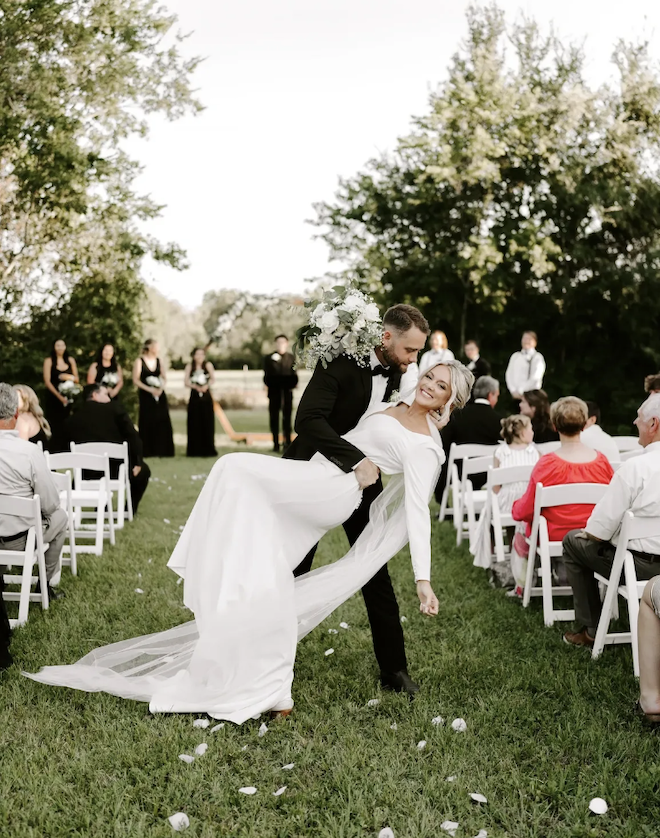 Bride and groom smile at the end of the aisle with an up-do and glam makeup. 